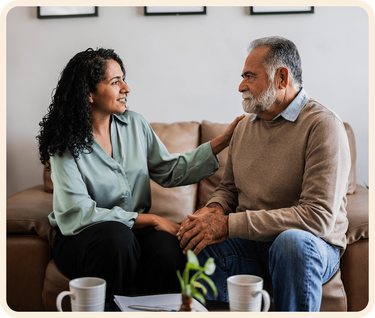Woman comforting elderly man on sofa